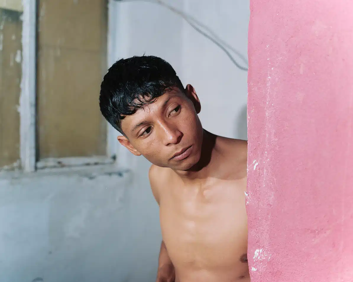 Felipe Romero Beltrán Retrato de un hombre joven, de complexión delgada, mirando hacia un lado desde detrás de una pared rosa, en la fotografía 'Amigo de El Friki', de Felipe Romero Beltrán.