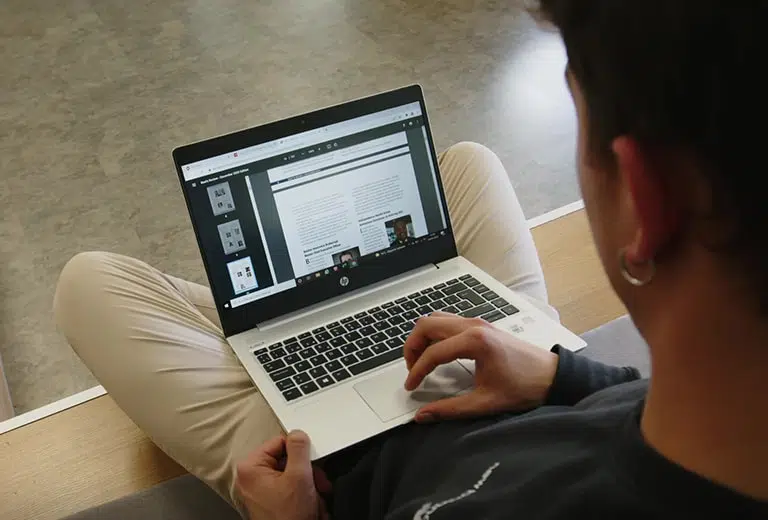 Persona revisando nuestras publicaciones en la página del Centro de Documentación de la Fundación MAPFRE, mientras navega por su laptop gris de con teclas negras en un entorno cómodo y relajado.